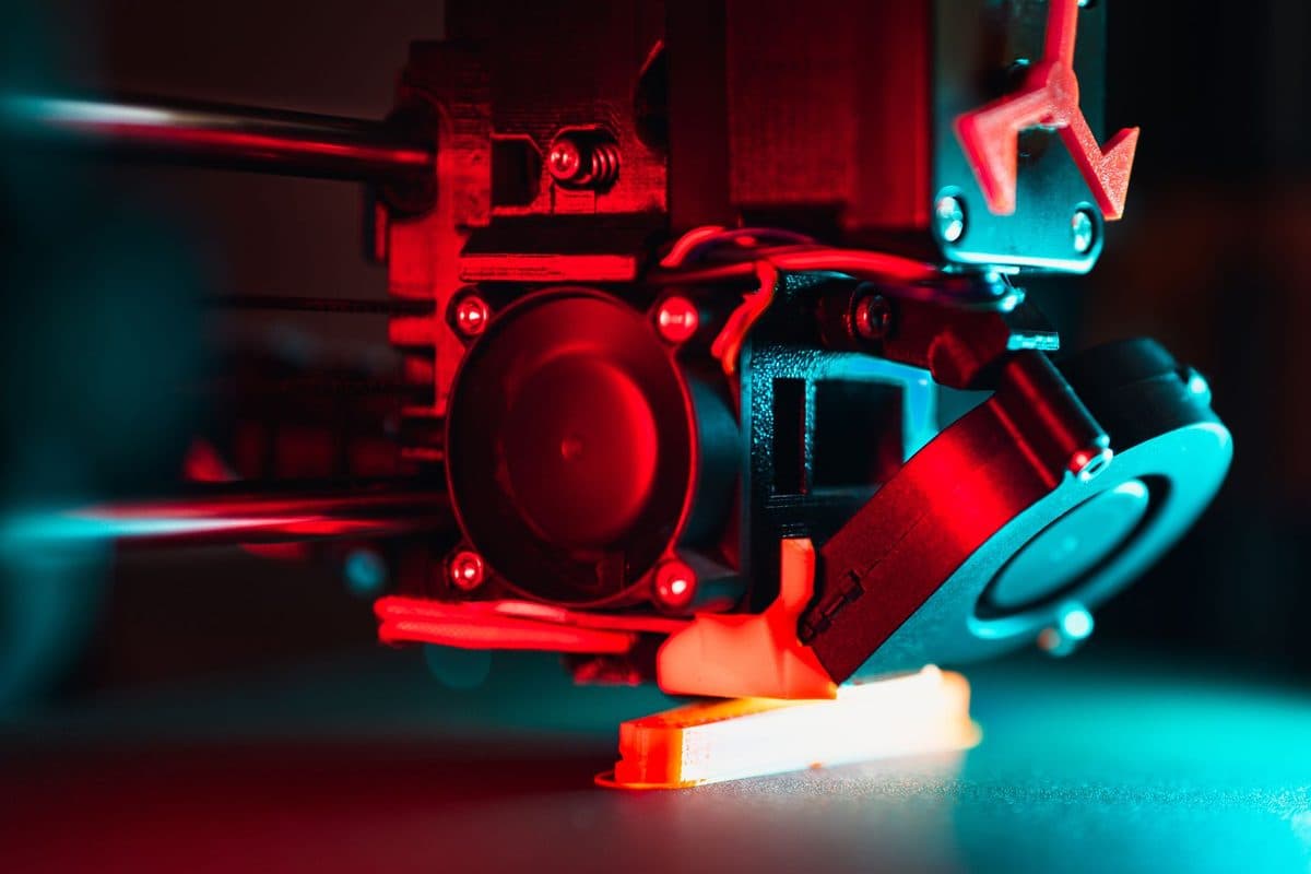 A 3D printer building a part close up, lit in red and blue