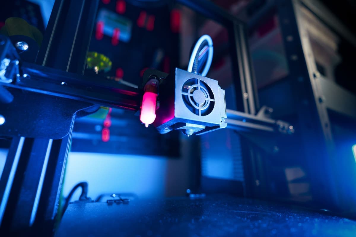 A close-up of an illuminated 3D printer part-way through a print