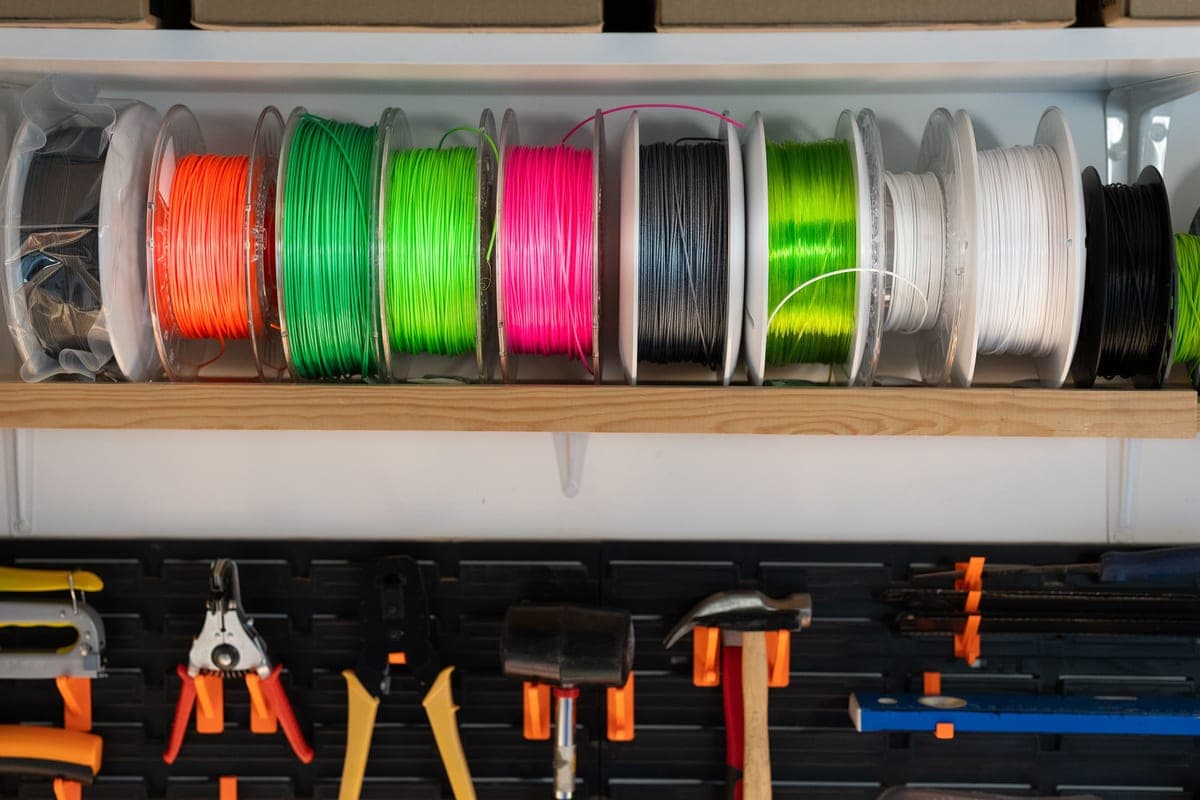 A filament spool loaded onto a 3D printer's spool holder, seen in low light