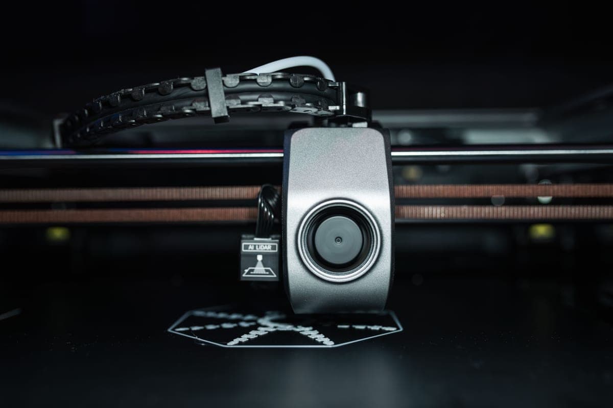 A close view of a 3D printer nozzle above a build plate