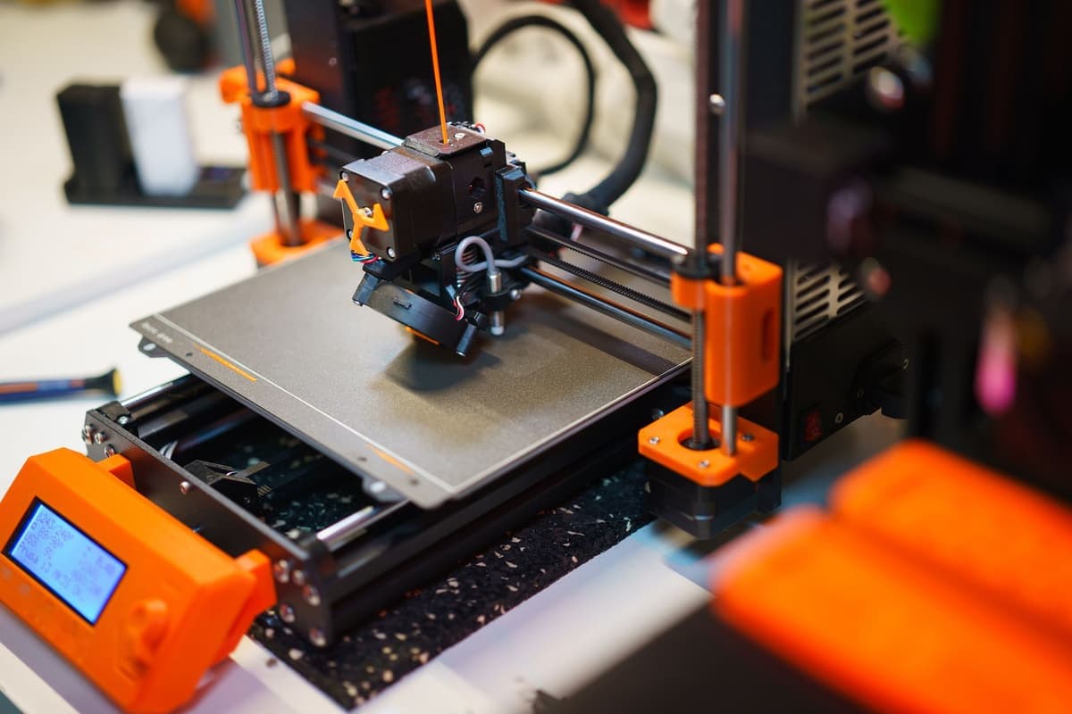 A 3D printer mid-print, building an object in orange filament