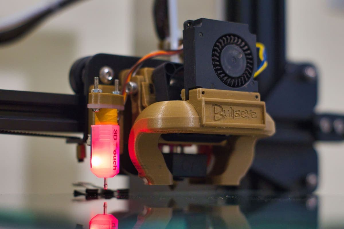 The nozzle of an enclosed desktop 3D printer part-way through a print
