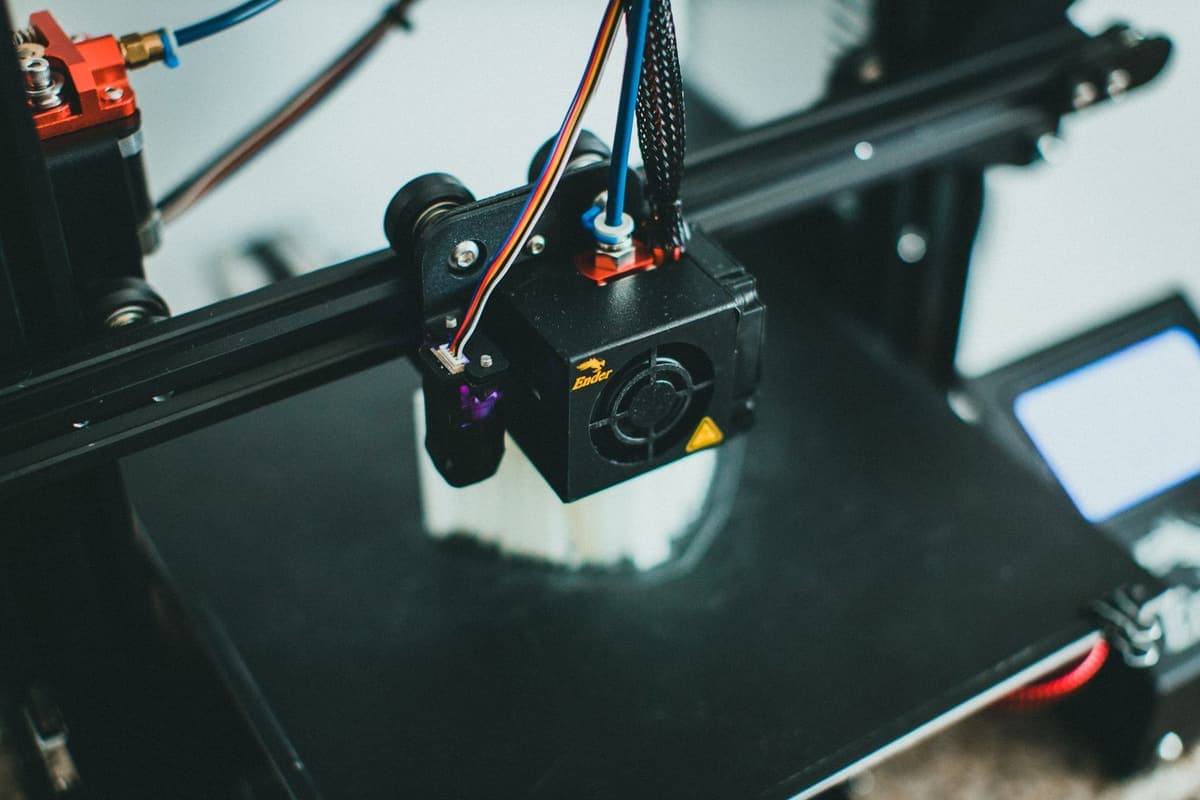 A close-up of a 3D printer mid-print, showing the cooling fan and print head