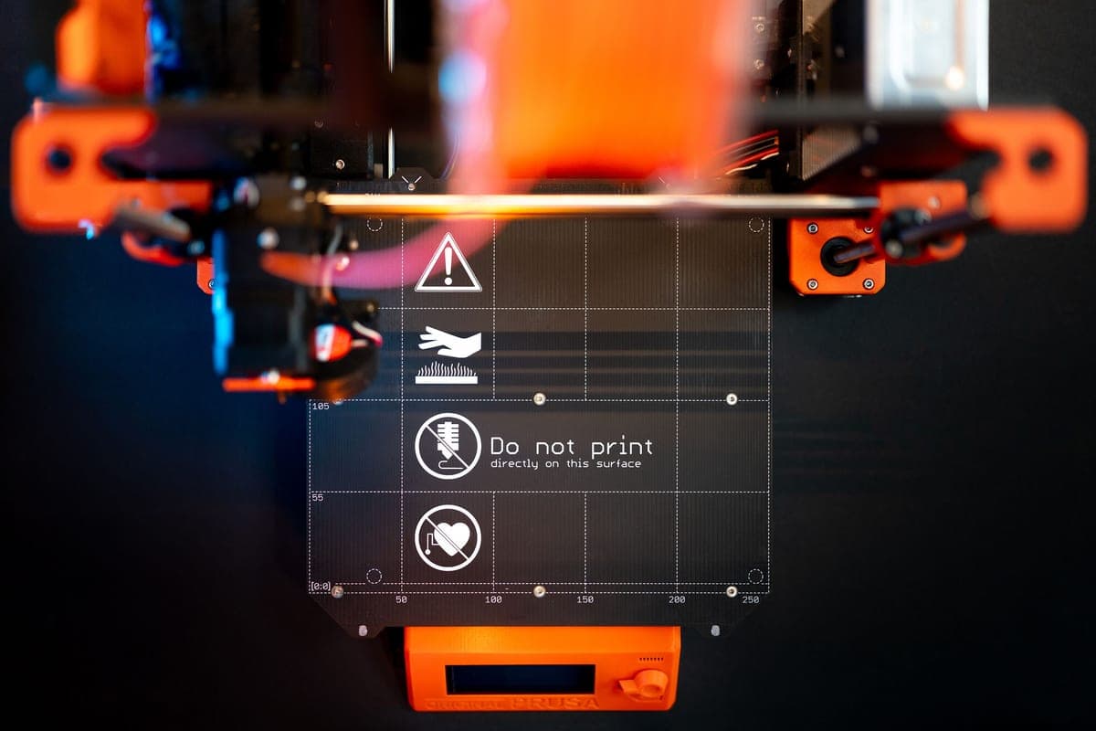 An open-frame 3D printer with a touchscreen, photographed against a dark backdrop