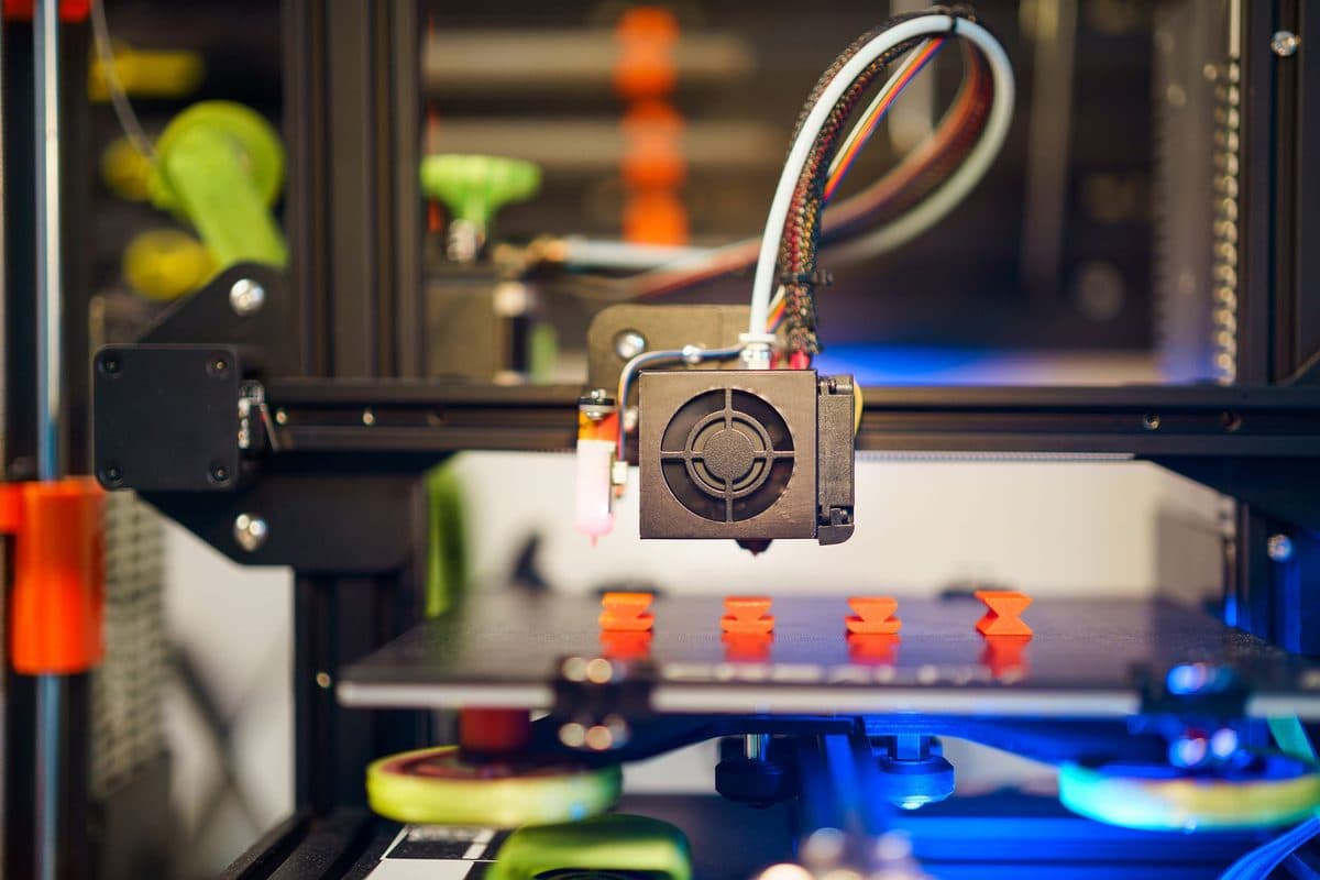 A desktop 3D printer part-way through printing small plastic pieces