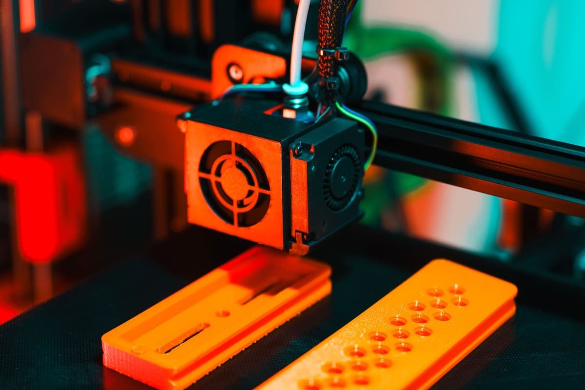 A 3D printer part-way through a long print, extruding orange plastic