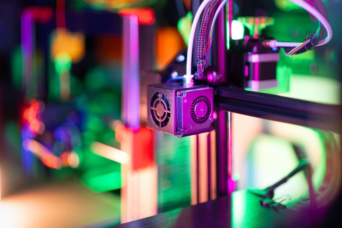 A 3D printer lit by colored lighting in a workshop
