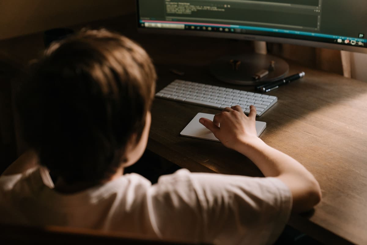 A teenager working at a computer in a warm indoor setting